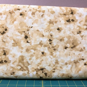 May include: Close-up of a fabric with a repeating pattern of abstract shapes in shades of brown, tan, and white. The fabric has a soft, textured appearance, suitable for various sewing and crafting projects. The design is reminiscent of a mosaic or a natural stone.