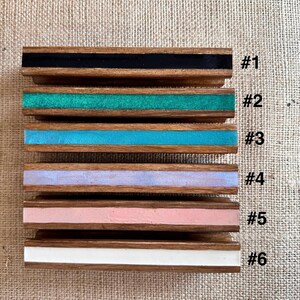 Puede incluir: Seis tiradores de cajón de madera con incrustaciones de resina de diferentes colores. Los tiradores están numerados del 1 al 6. Las incrustaciones son negras, verdes, azules, moradas, rosas y blancas.