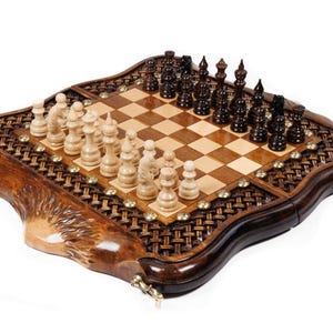 May include: A wooden chess set with a decorative, carved border. The chessboard is made of light and dark wood squares, with chess pieces arranged on the board. The chess pieces are light and dark brown.