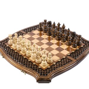 May include: A wooden chess set with a decorative border. The chessboard is brown and tan with chess pieces in light and dark wood. The set is displayed on a white background.