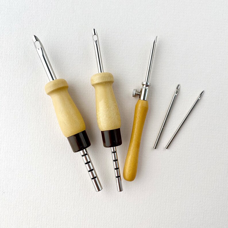 May include: Five tools for leather crafting, including three awls with wooden handles and metal tips, and two smaller needles. The awls have black accents on the handles.