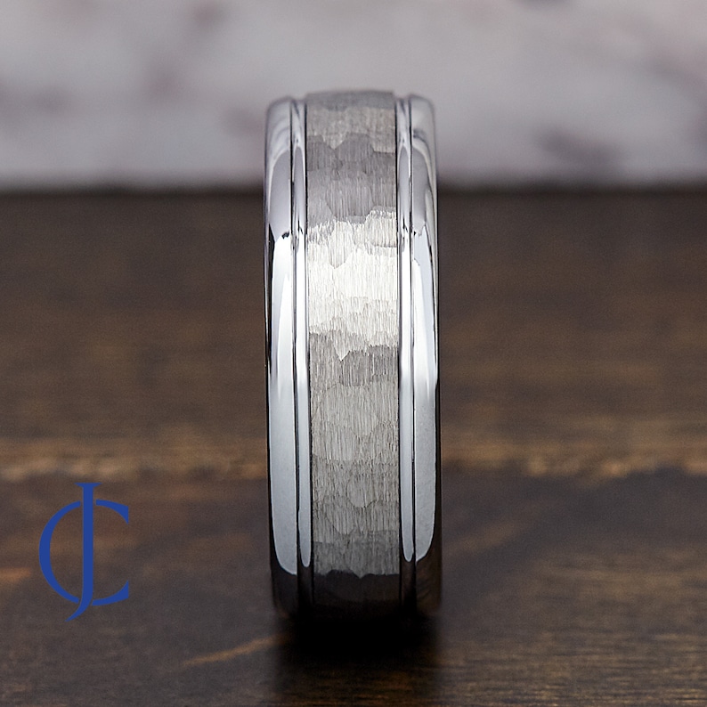 Puede incluir: Un anillo de carburo de tungsteno plateado con acabado martillado y dos bordes biselados pulidos.