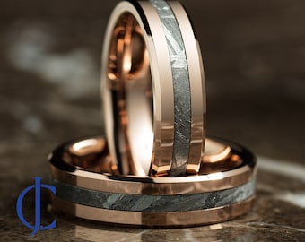 May include: Two rose gold wedding bands with a black meteorite inlay. The bands are beveled and have a polished finish.