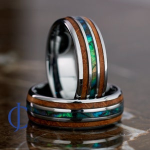 May include: Two silver tungsten carbide rings with a brown wood inlay and green abalone shell accents.