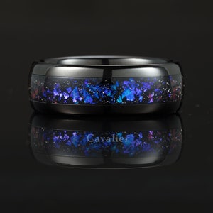 May include: A black tungsten carbide ring with a blue and purple galaxy-inspired inlay. The ring has a polished finish and a comfortable fit.