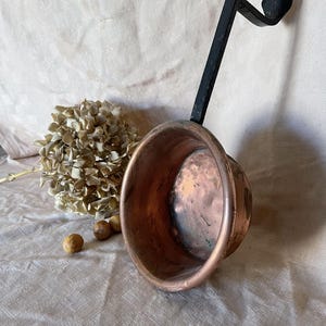 Antieke koperen pan met lang ijzeren handvat op voet