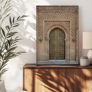 Puede incluir: Impresi&oacute;n enmarcada de una puerta arqueada ornamentada con intrincadas tallas y una puerta dorada. El detalle arquitect&oacute;nico se presenta sobre una fachada de piedra neutra. La impresi&oacute;n se exhibe sobre un mueble de madera.