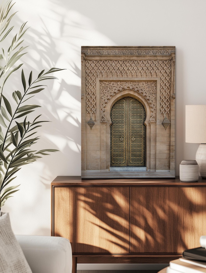 Puede incluir: Impresi&oacute;n enmarcada de una puerta arqueada ornamentada con intrincadas tallas y una puerta dorada. El detalle arquitect&oacute;nico se presenta sobre una fachada de piedra neutra. La impresi&oacute;n se exhibe sobre un mueble de madera.