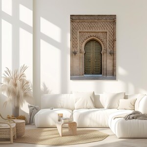 Puede incluir: Impresi&oacute;n enmarcada de una puerta arqueada ornamentada con un dise&ntilde;o tallado detallado. La puerta es dorada y el marco es de color marr&oacute;n claro. La impresi&oacute;n cuelga sobre un sof&aacute; seccional blanco en un sal&oacute;n moderno y luminoso.