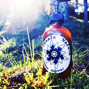 May include: A brown glass bottle with a pump dispenser and a white label that says "Innata Natura Cosmetica Natural". The bottle is sitting on a bed of green moss.