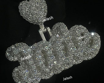 May include: A silver charm with the word "Jala" spelled out in large, sparkly letters. The charm is attached to a small, heart-shaped charm, also covered in sparkling stones.