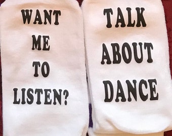 May include: A pair of white socks with black text. One sock says "Want me to listen?" and the other sock says "Talk about dance."