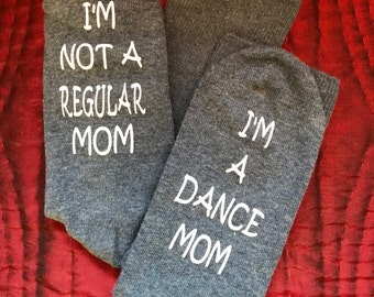 May include: A pair of gray socks with white text. One sock says "I'm not a regular mom" and the other sock says "I'm a dance mom".