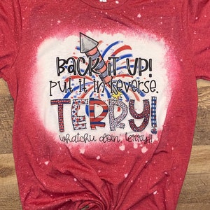 May include: Red t-shirt with a bleached design featuring a firework, the text "Back it up! Put it in reverse. TERRY! Whatchu doin, Terry?!", and red, white, and blue accents.