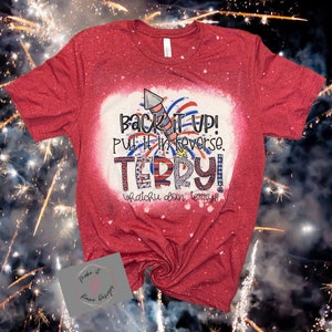 May include: Red t-shirt with a white bleach design featuring a firework, the text "Back it up! Put it in reverse. TERRY! Whatchu doin, Terry!!" and a red, white, and blue design.