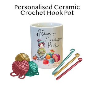 May include: A white ceramic crochet hook pot with a personalised design featuring a girl crocheting and the text "Alisa's Crochet Hooks". The pot is surrounded by colourful yarn balls and crochet hooks.
