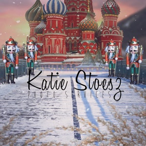 May include: Five toy nutcracker soldiers stand on a snowy bridge in front of a red and white building with colorful onion domes. The building is decorated with lights and snow is falling. The text "Katie Stoesz Photo Services" is written on the bridge.