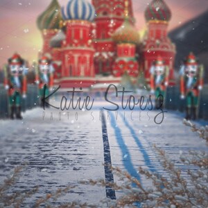 May include: A snowy winter scene with a red and white castle in the background. Four nutcracker figurines stand on a bridge leading to the castle. The text "Katie Stoesz Photo Services" is visible in the foreground.