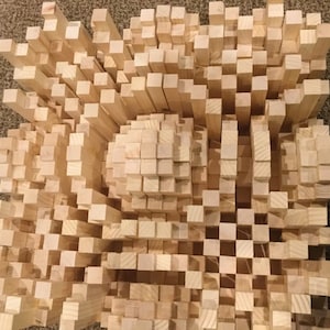 Könnte beinhalten: Ein Holz-Schalldiffusor aus vielen kleinen Holzblöcken. Die Blöcke sind in einem Muster angeordnet, das einen dreidimensionalen Effekt erzeugt. Der Diffusor ist so konzipiert, dass er Schallwellen absorbiert und Echos in einem Raum reduziert.
