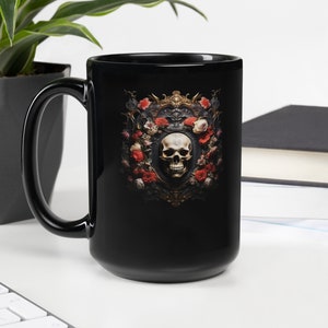 May include: Black ceramic mug with a skull surrounded by red and white roses in a gold frame. The skull has a black eye socket and a white bone structure.