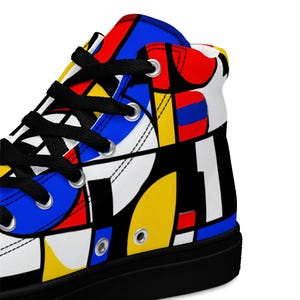 May include: High-top canvas trainer with a vibrant geometric pattern. The shoe has a black sole, black laces, and a design of red, blue, yellow, and white shapes. The number "1" is displayed on the side.
