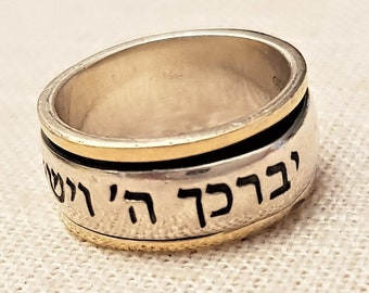 May include: A silver ring with a gold band and Hebrew writing. The writing says "ברוך אתה" which translates to "Blessed are you".