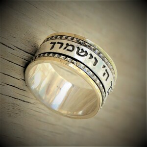 May include: A silver and gold spinning ring with Hebrew text that reads "Ha Shem" which means "The Name".