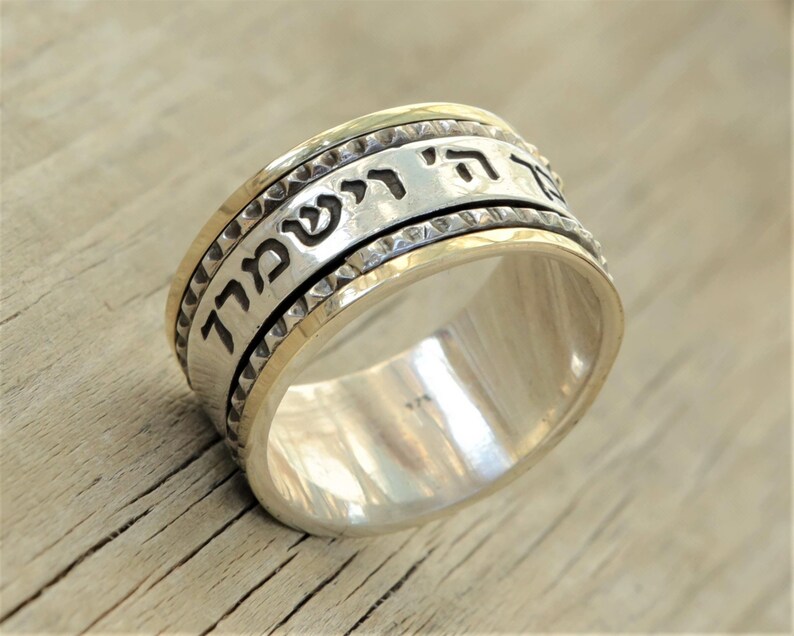 May include: A silver and gold spinning ring with Hebrew text that reads "Ani L'Dodi V'Dodi Li" which translates to "I am my beloved's and my beloved is mine".