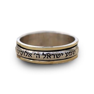 May include: A silver and gold spinning ring with Hebrew text that reads "Shema Yisrael Adonai Eloheinu Adonai Echad" which translates to "Hear O Israel, the Lord our God, the Lord is One".