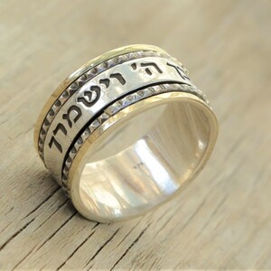 May include: A silver spinning ring with a gold band and Hebrew text. The text reads "לֹא תִירָא" which translates to "Do not be afraid".