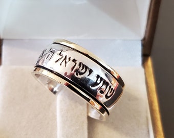 May include: A silver spinning ring with Hebrew text engraved on the band. The ring is in a white box.