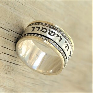 May include: A silver and gold spinning ring with Hebrew text that reads "Ha Shem" which means "The Name".