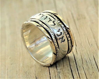 May include: A silver ring with a gold band and Hebrew writing. The ring is engraved with the words "Chai" and "Mazel Tov".