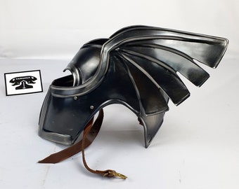 May include: A black metal helmet with a winged design. The helmet has a leather strap and is made of metal.