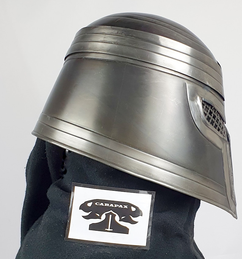 May include: A silver helmet with a black fabric lining and a black and white sticker with the text "CARAPAX" on it.