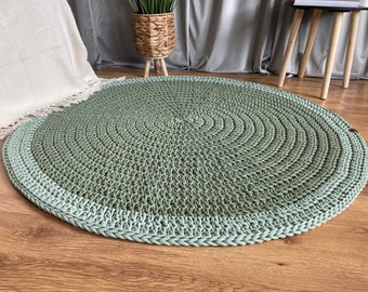 May include: A round, green and light green crocheted rug with a textured surface.