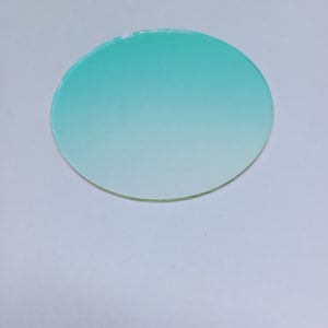 May include: A round, clear glass coaster with a gradient of light blue to white.
