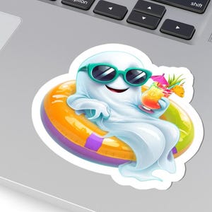 May include: A die-cut sticker featuring a white ghost wearing teal sunglasses, relaxing in a bright orange and green inflatable pool ring while holding a tropical cocktail with a small pink umbrella and a slice of pineapple as a garnish.