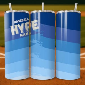 May include: Three blue insulated tumblers with lids and straws. The tumblers have a gradient design of dark to light blue. The text "BASEBALL HYPE MAMA" is printed on the front in white block letters. The tumblers are on a baseball field.