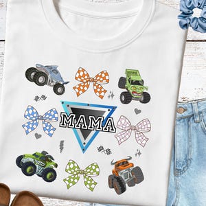 May include: White sweatshirt with monster truck designs, bows, and the word "MAMA" in a blue triangle. The trucks are in green, orange, and blue, with black wheels. Bows are in orange, blue, and green checkered patterns.