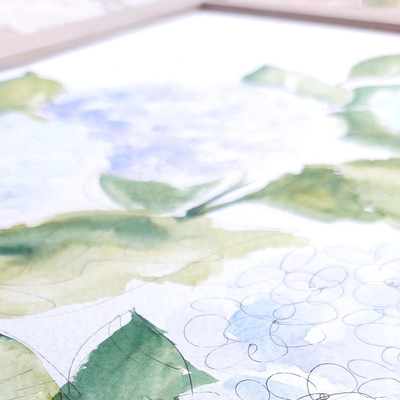 Pode incluir: Pintura em aquarela de hort&ecirc;nsias em tons de azul, verde e branco. A obra apresenta pinceladas soltas e um trabalho de linha delicado, capturando as texturas macias das flores e das folhas. A pintura &eacute; emoldurada.