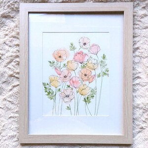 Pode incluir: Uma pintura em aquarela emoldurada de flores estilizadas em tons de p&ecirc;ssego, rosa e amarelo, com folhas e caules verdes. A obra de arte &eacute; colocada sobre um fundo branco e emoldurada em uma moldura de madeira clara.