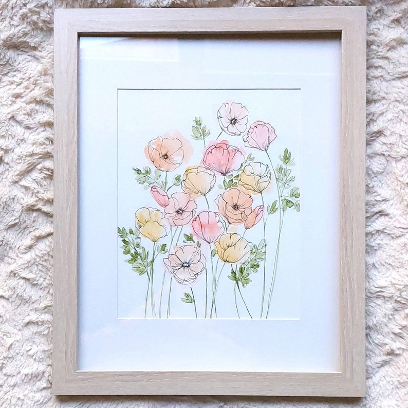 Pode incluir: Uma pintura em aquarela emoldurada de flores estilizadas em tons de p&ecirc;ssego, rosa e amarelo, com folhas e caules verdes. A obra de arte &eacute; colocada sobre um fundo branco e emoldurada em uma moldura de madeira clara.