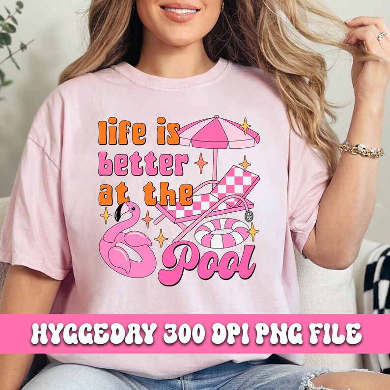 Pode incluir: Camiseta rosa com um design gr&aacute;fico que diz "A vida &eacute; melhor na piscina" com um flamingo, uma espregui&ccedil;adeira e um flutuador de piscina.