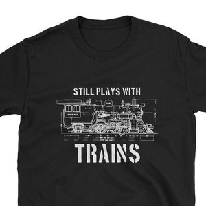 May include: Black t-shirt with a white graphic of a train and the text "Still Plays With Trains".
