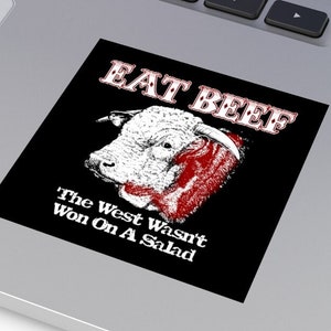 Op de afbeelding: Een zwart-witte sticker met een rood-witte stierenillustratie en de tekst "EAT BEEF" en "The West Wasn't Won On A Salad".