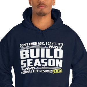May include: Navy blue hooded sweatshirt with white text that reads "Don't even ask. I can't. It's Build Season. Normal life resumes TBD."
