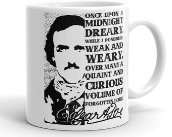 Puede incluir: Taza de cerámica blanca con una ilustración en blanco y negro de Edgar Allan Poe y una cita de su poema "El Cuervo". La cita dice: "Once upon a midnight dreary, while I pondered, weak and weary, over many a quaint and curious volume of forgotten lore..."