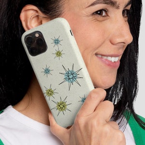 May include: A white phone case with a pattern of blue and green stars. The case is made of a textured material and has a cutout for the camera lens.