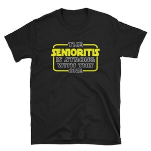May include: Black t-shirt with a yellow graphic that says "The Senioritis Is Strong With This One" in a Star Wars-inspired font.